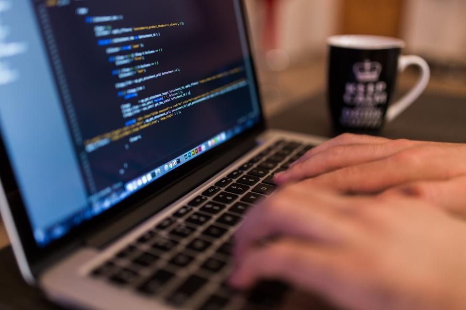 Hands typing code on a laptop