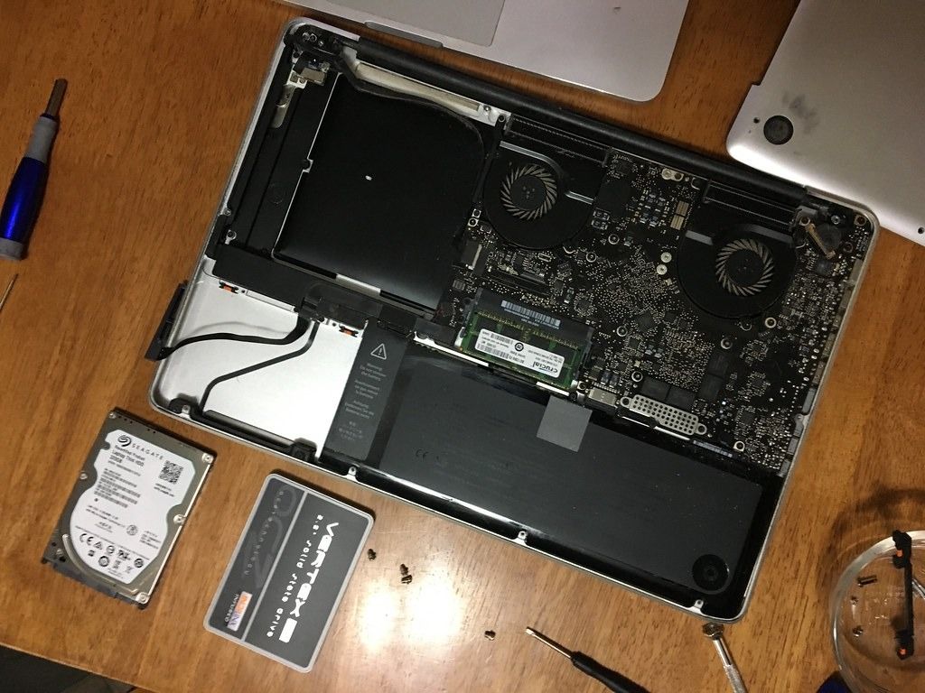 Open laptop on a workbench with its drives removed