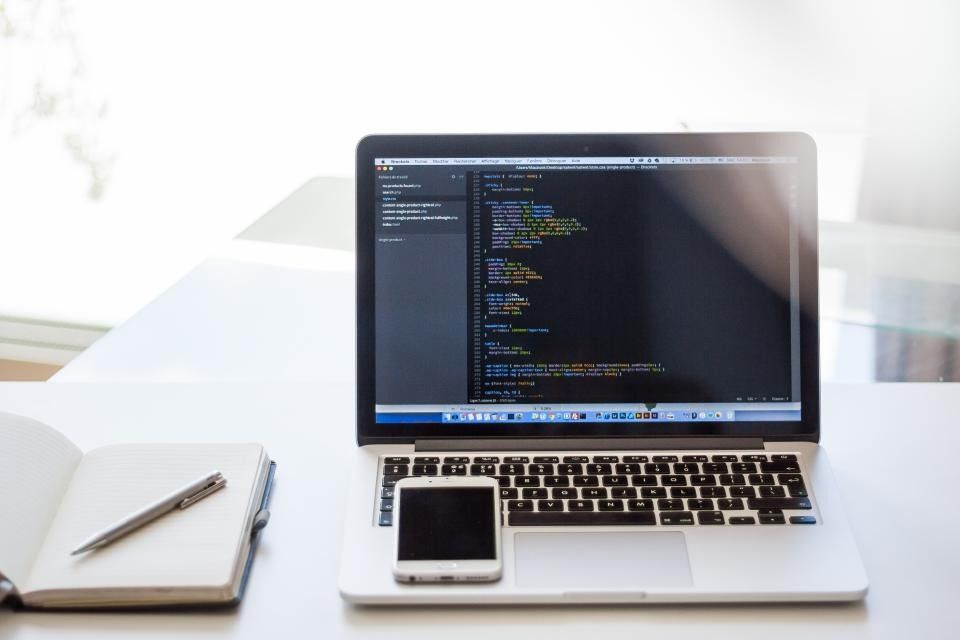 Laptop, phone and notebook on a white desk