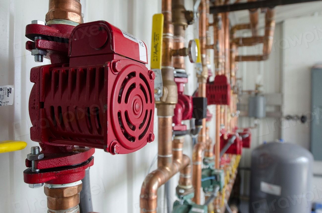 Red industrial pump and copper pipework in a plant room